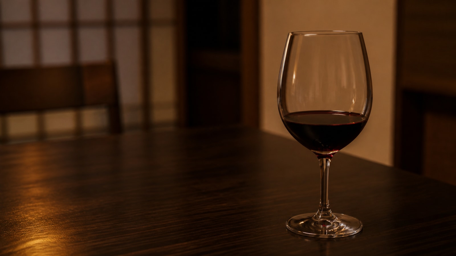 夜の食卓に置かれた、飲みかけの赤ワインのグラス